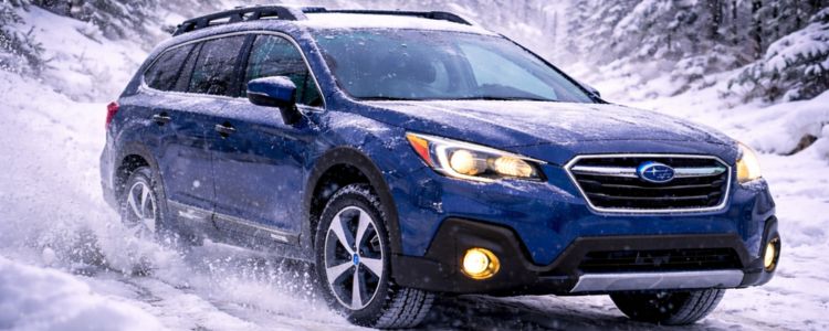 Subaru Outback driving through heavy winter snowfall on a snowy road, showcasing all-wheel drive confidence in harsh conditions.