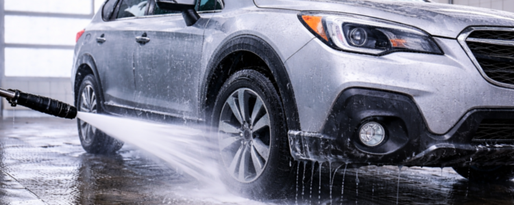 Subaru SUV being washed indoors at a car wash to remove winter road salt and prevent rust buildup.